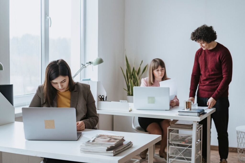 Group of colleagues working together in a bright, modern office space with laptops.